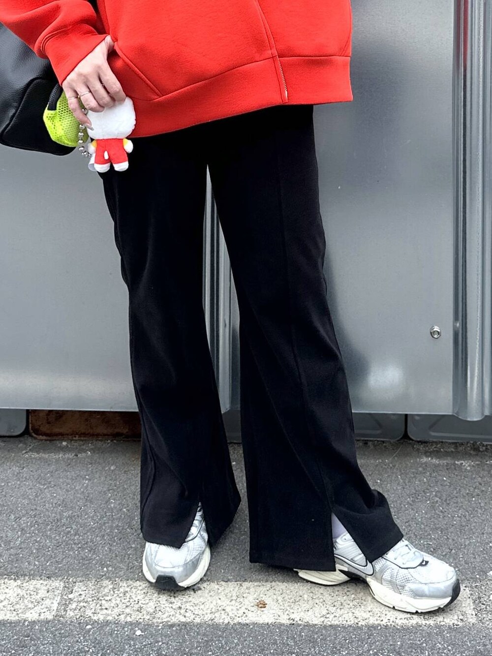 ブラック系のショルダーバッグ、レッド系のパーカー、ブラック系のその他パンツを着用したレディースの秋コーディネートの5枚目の写真