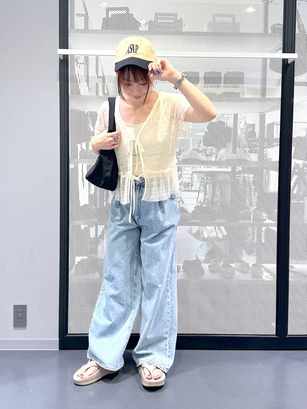 ブルー系のデニムパンツ、ブラック系のハンドバッグ、ベージュ系のサンダルを着用したレディースの夏コーディネートの2枚目の写真