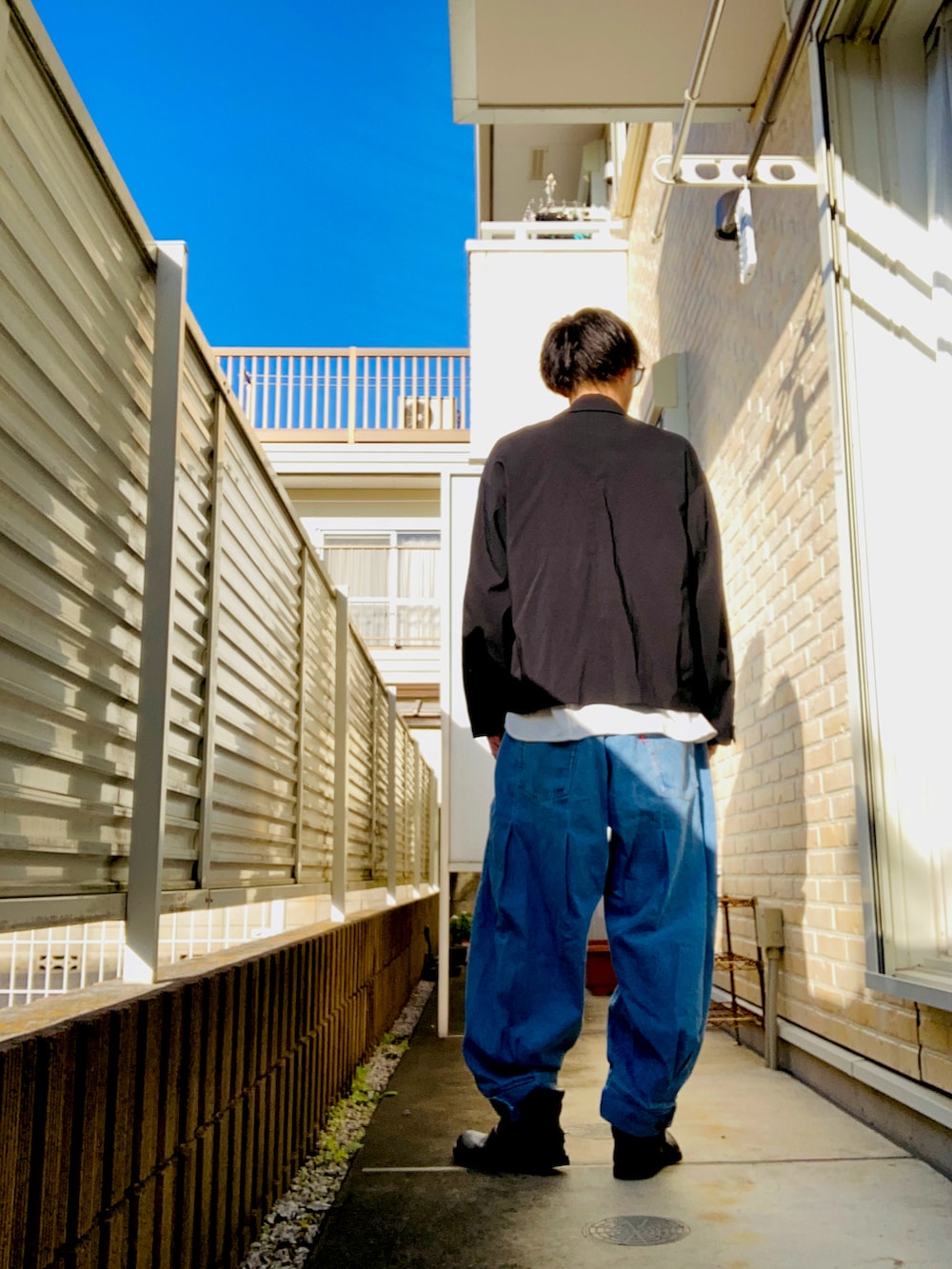 ブラック系のブルゾン、ホワイト系のTシャツ/カットソー、ブルー系のデニムパンツを着用したメンズの秋コーディネートの2枚目の写真