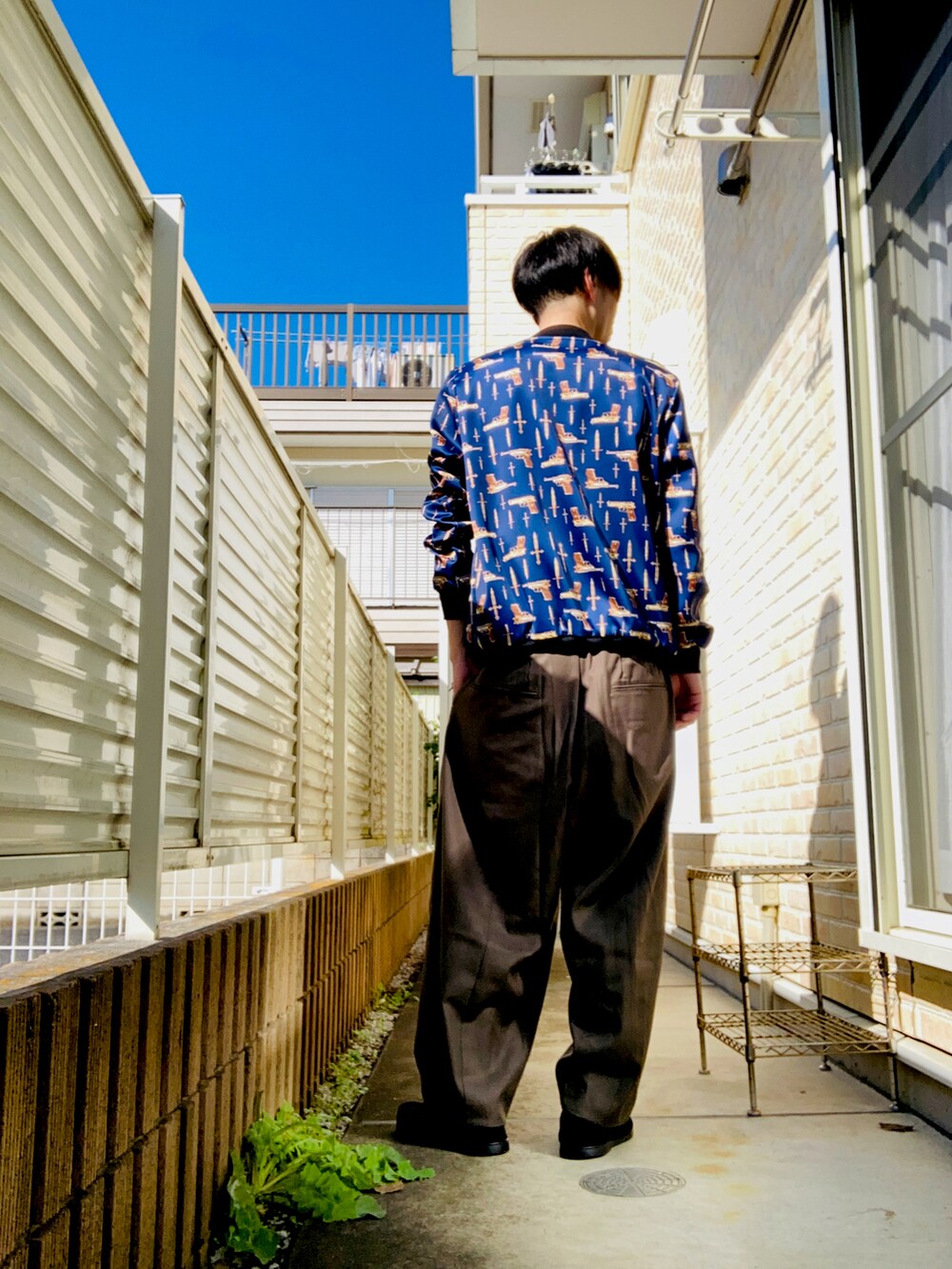 ブルー系のブルゾン、ホワイト系のタンクトップ、グリーン系のスラックスを着用したメンズの秋コーディネートの3枚目の写真