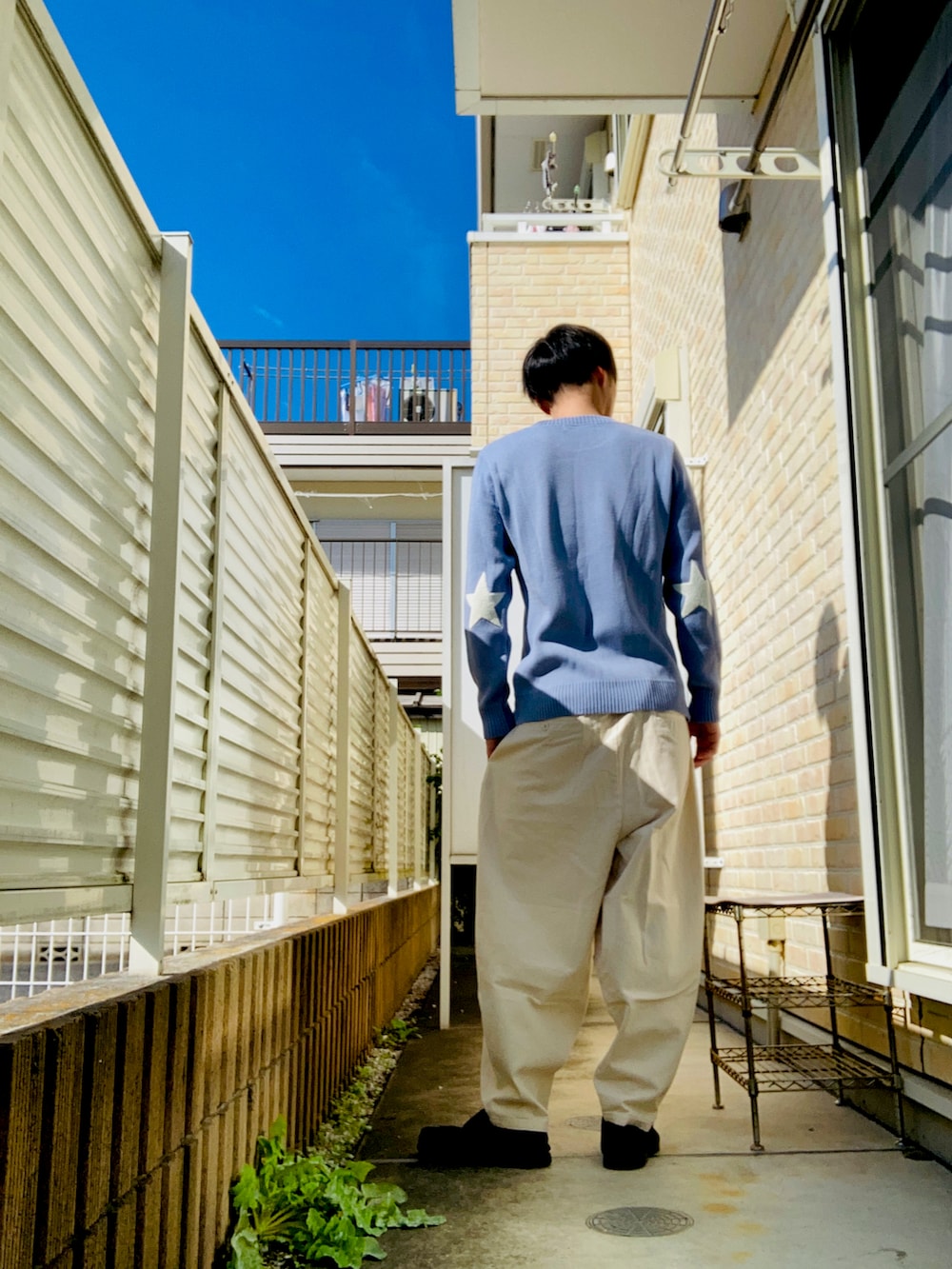 ブルー系のニット/セーター、ホワイト系のその他パンツ、ブラック系のスニーカーを着用したメンズの秋コーディネートの2枚目の写真