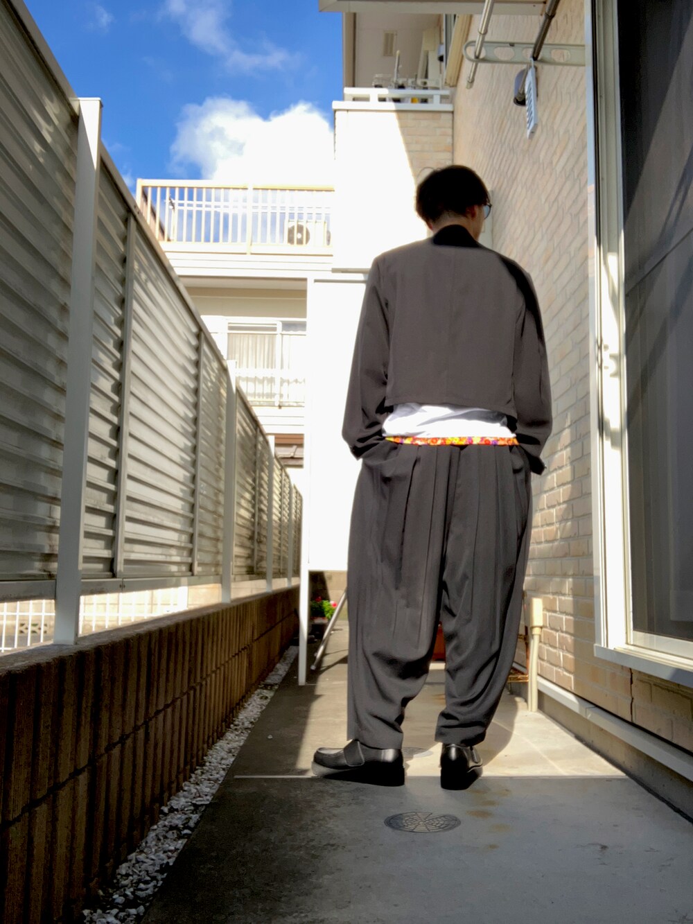 ブラック系のテーラードジャケット、ホワイト系のTシャツ/カットソー、ブラック系のスラックスを着用したメンズの秋コーディネートの2枚目の写真