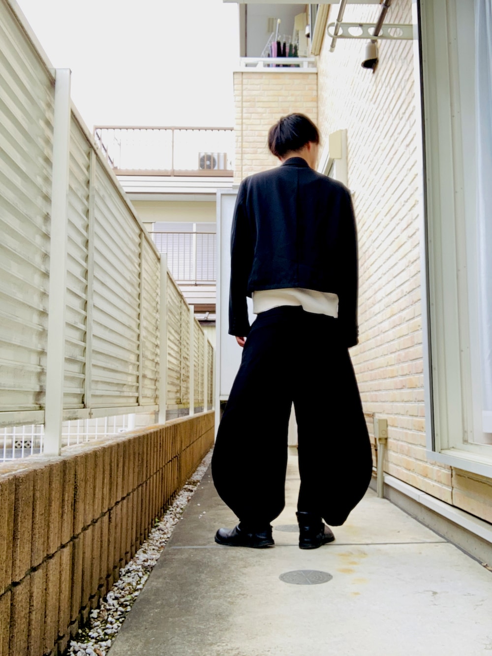 ブラック系のテーラードジャケット、ホワイト系のタンクトップ、ベージュ系のベストを着用したメンズの春コーディネートの2枚目の写真