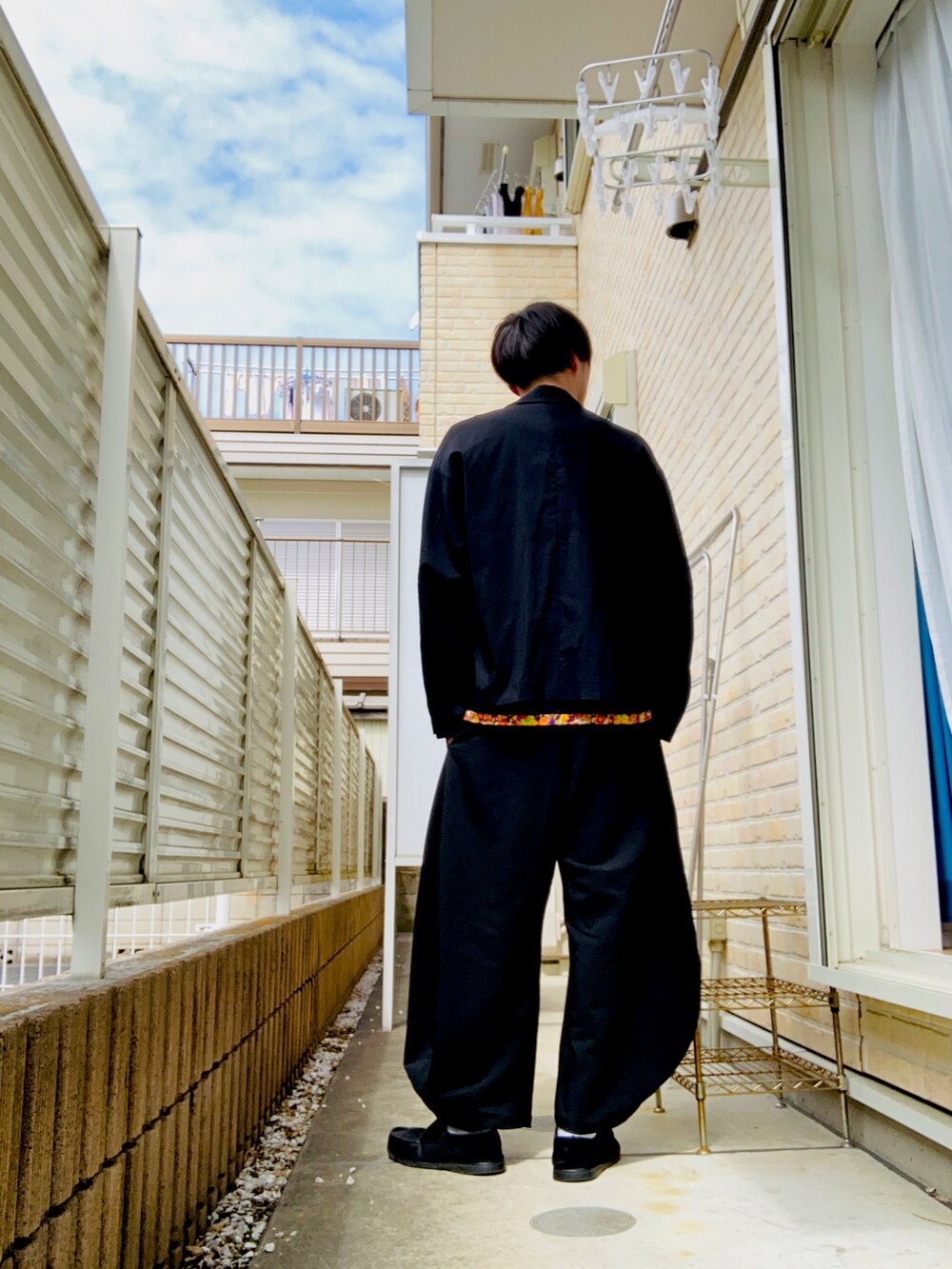 ブラック系のブルゾン、ブラック系のTシャツ/カットソー、ブラック系のスラックスを着用したメンズの春コーディネートの2枚目の写真