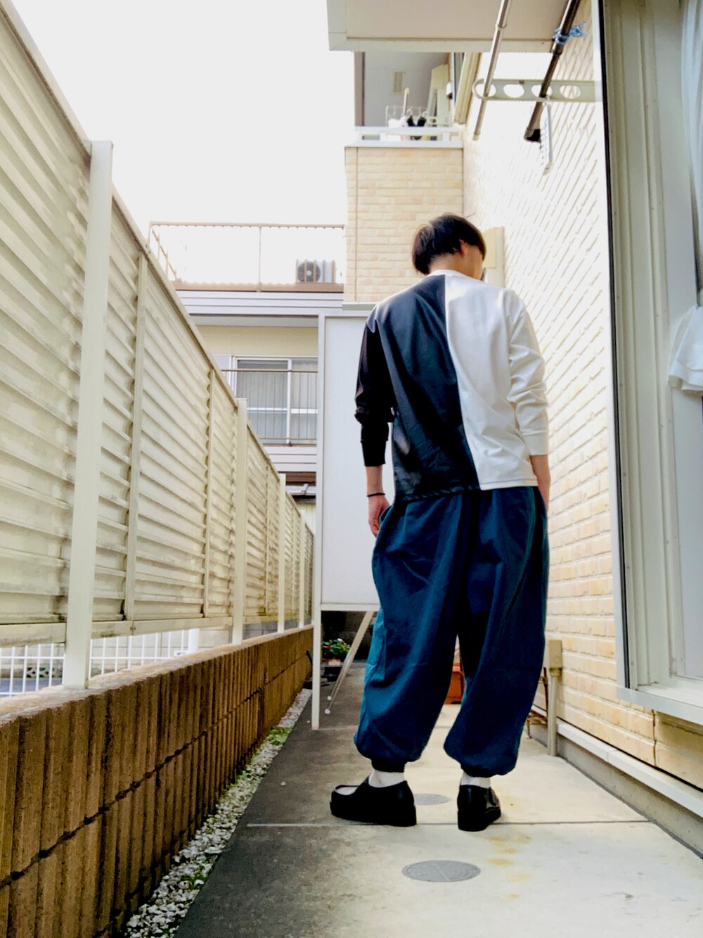 ホワイト系のTシャツ/カットソー、ブルー系のその他パンツ、ブラック系のスニーカーを着用したメンズの秋コーディネートの2枚目の写真