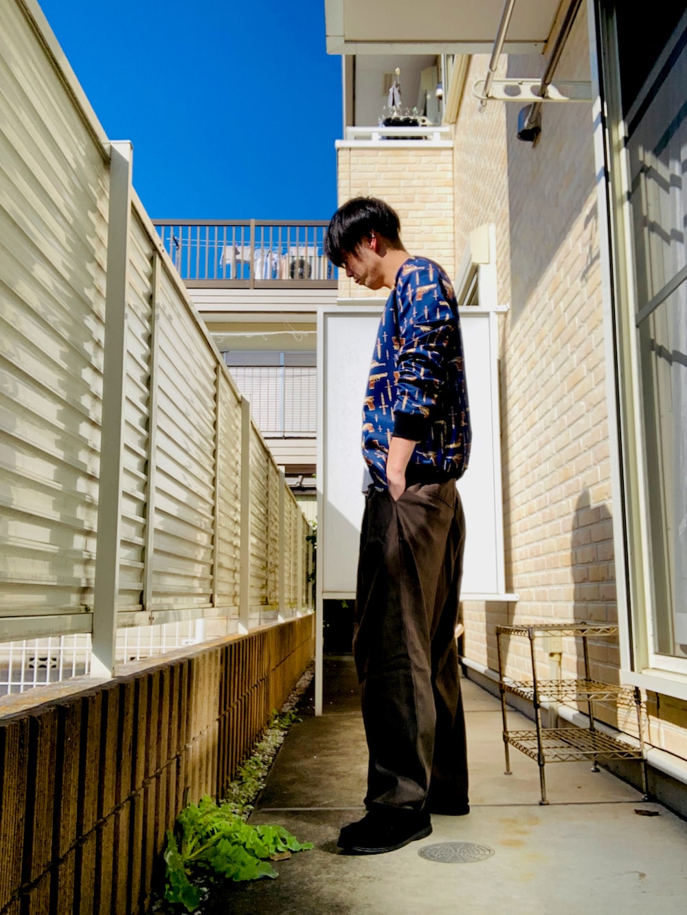 ブルー系のブルゾン、ホワイト系のタンクトップ、グリーン系のスラックスを着用したメンズの秋コーディネートの2枚目の写真