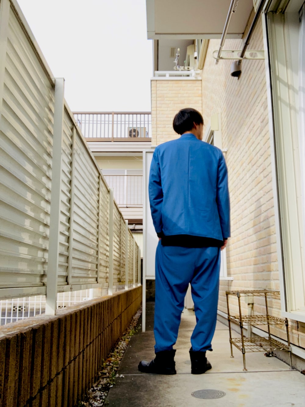 ブルー系のノーカラージャケット、ブラック系のニット/セーター、ブルー系のその他パンツを着用したメンズの冬コーディネートの2枚目の写真