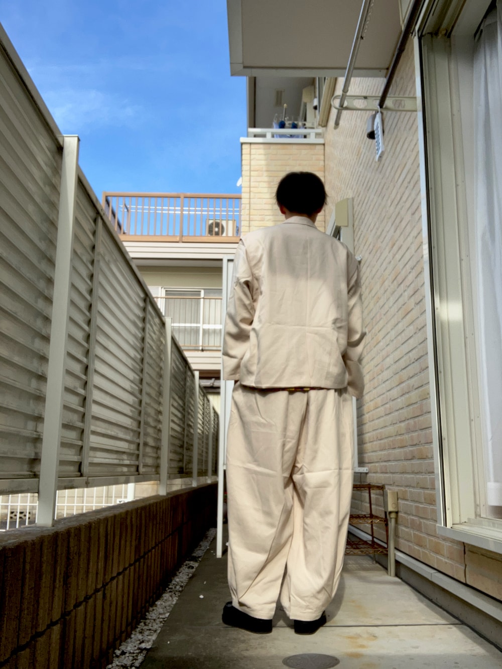 ホワイト系のテーラードジャケット、ホワイト系のその他パンツ、ブラック系のTシャツ/カットソーを着用したメンズの秋コーディネートの2枚目の写真