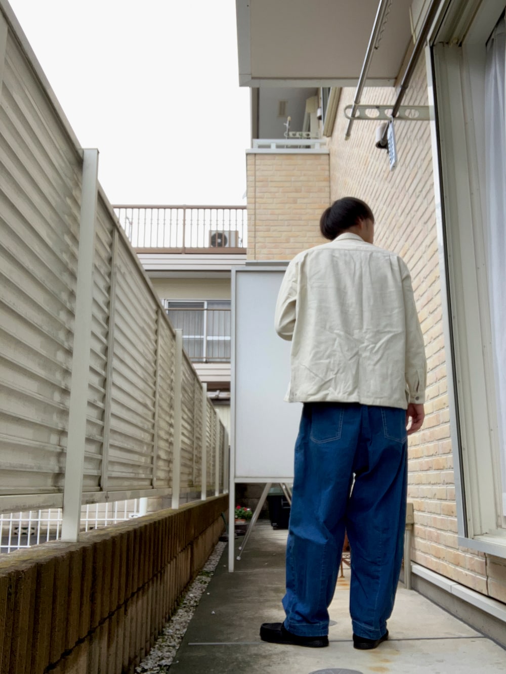 ホワイト系のシャツ/ブラウス、ブラック系のタンクトップ、ブルー系のデニムパンツを着用したメンズの秋コーディネートの2枚目の写真