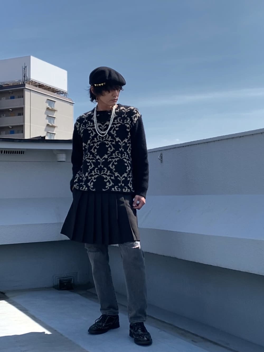 ブラック系のニット/セーター、ブラック系のスカート、グレー系のデニムパンツを着用したメンズの春コーディネートの2枚目の写真