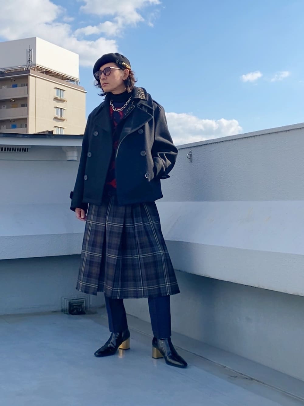 ブラック系のピーコート、レッド系のニット/セーター、ブラウン系のスカートを着用したメンズの冬コーディネートの2枚目の写真