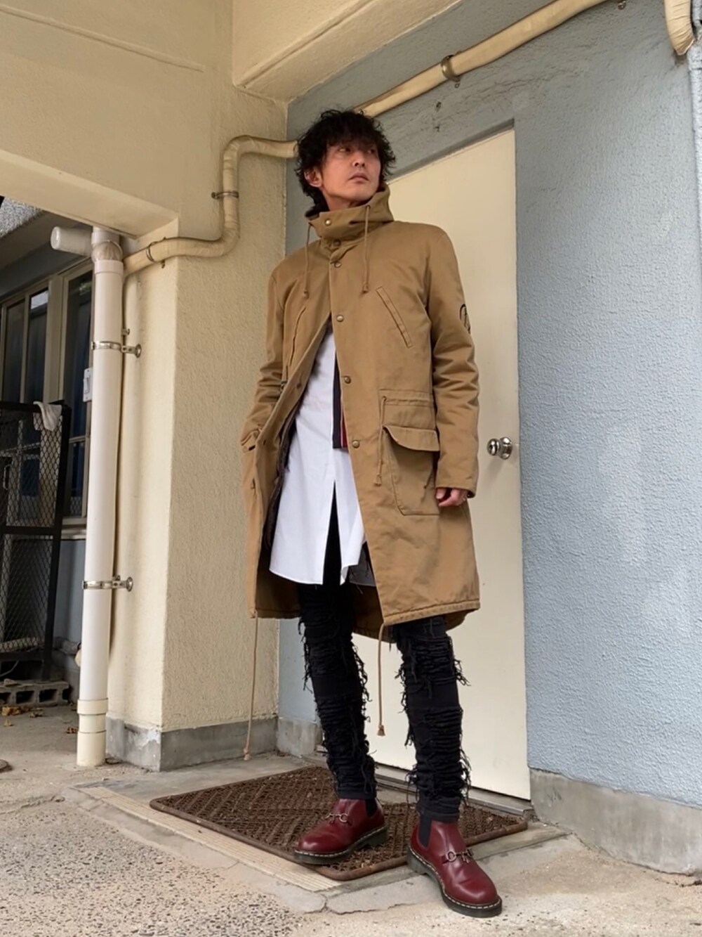 ベージュ系のモッズコート、ブラック系のデニムパンツ、レッド系のブーツを着用したメンズの冬コーディネートの2枚目の写真