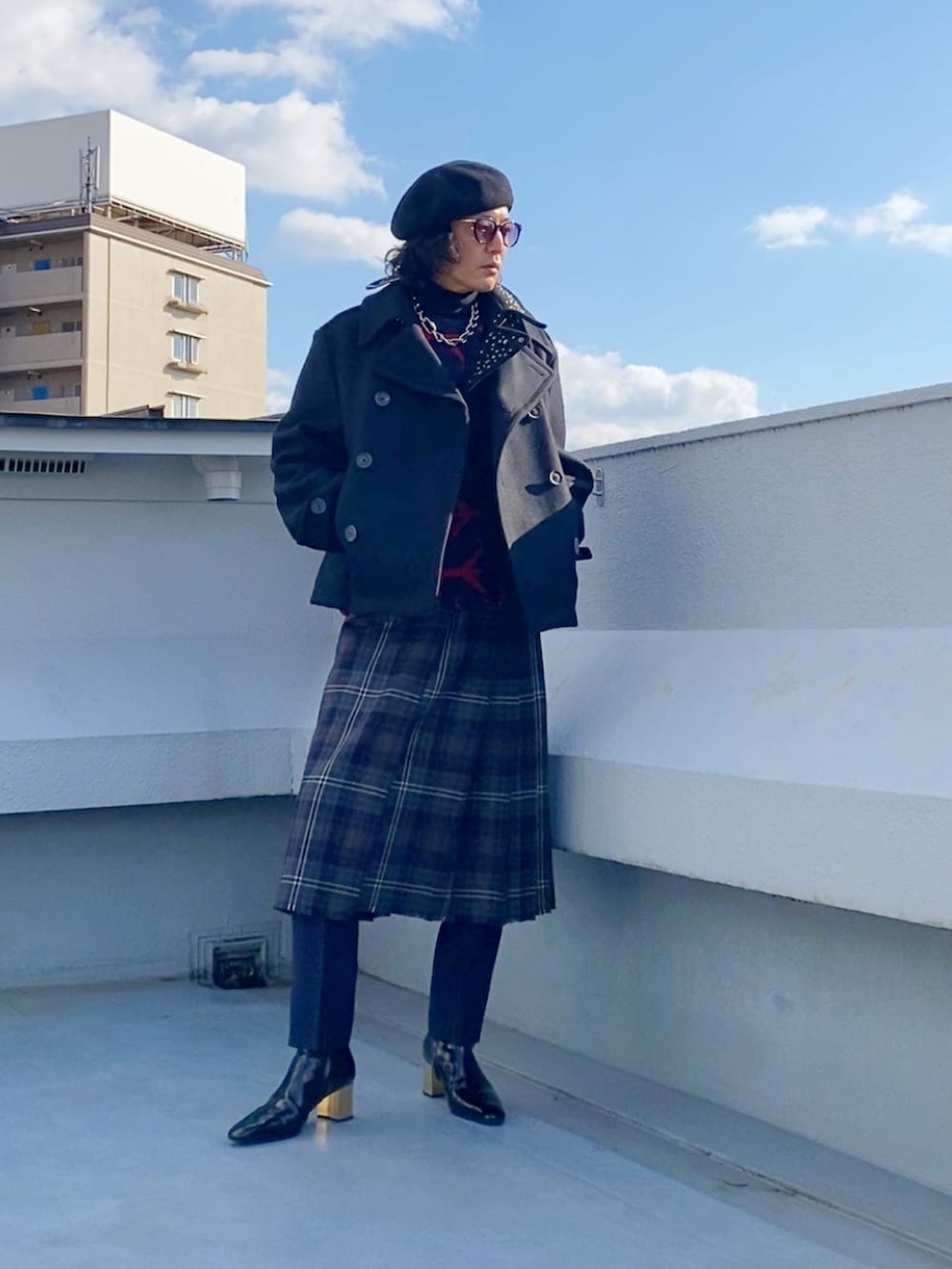 ブラック系のピーコート、レッド系のニット/セーター、ブラウン系のスカートを着用したメンズの冬コーディネートの4枚目の写真