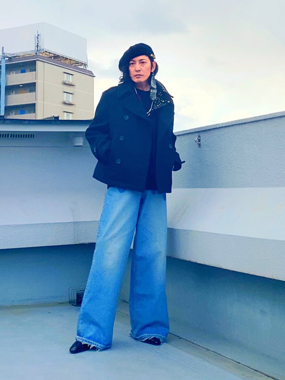 ブラック系のピーコート、レッド系のニット/セーター、ブルー系のデニムパンツを着用したメンズの冬コーディネートの2枚目の写真