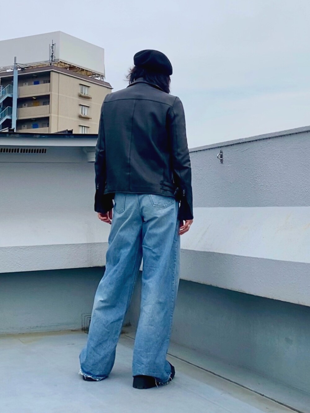 ブラック系のライダースジャケット、ブラック系のニット/セーター、ブルー系のデニムパンツを着用したメンズの春コーディネートの4枚目の写真