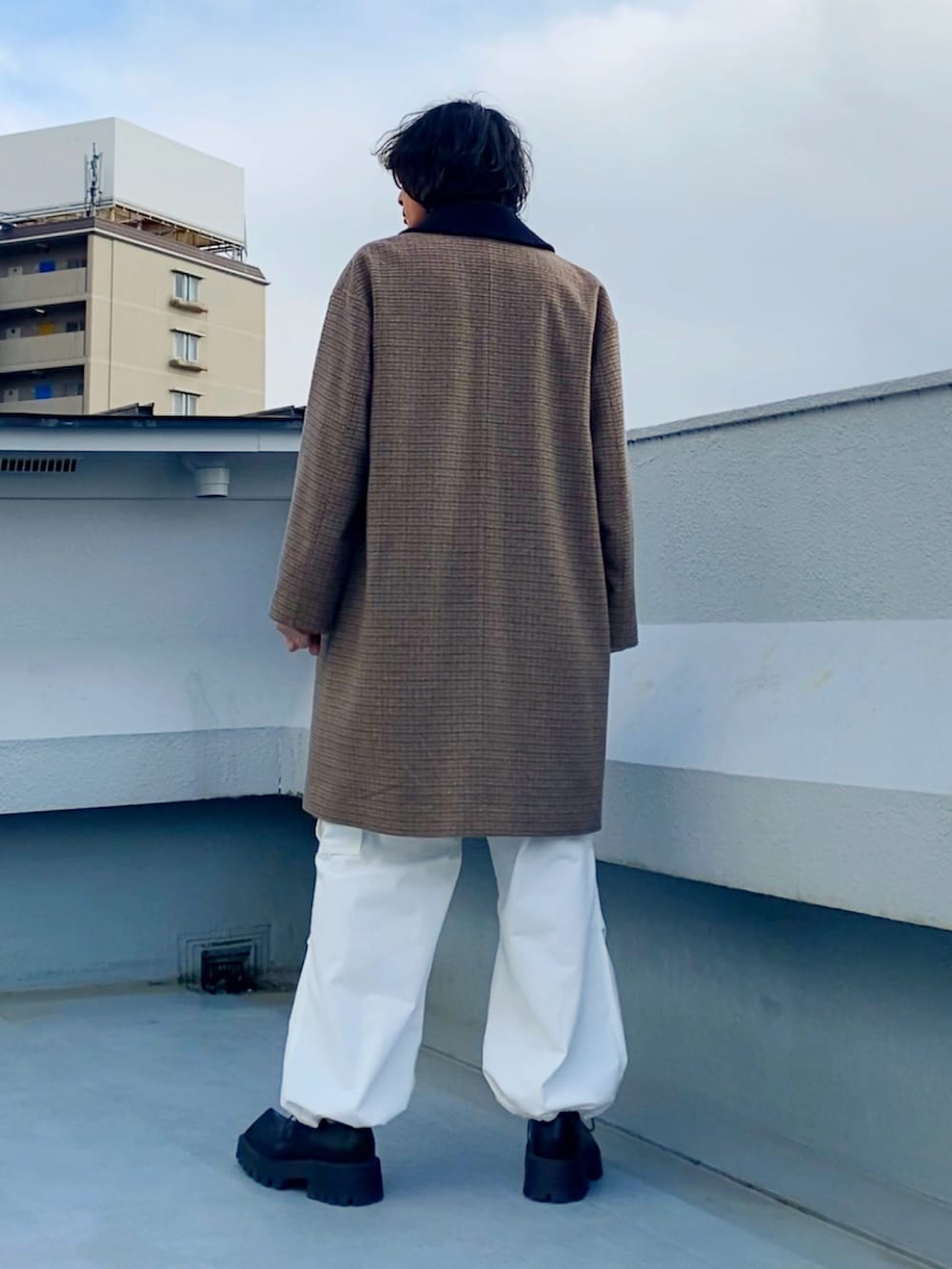 ブラック系のライダースジャケット、ブラウン系のステンカラーコート、ホワイト系のカーゴパンツを着用したメンズの冬コーディネートの5枚目の写真