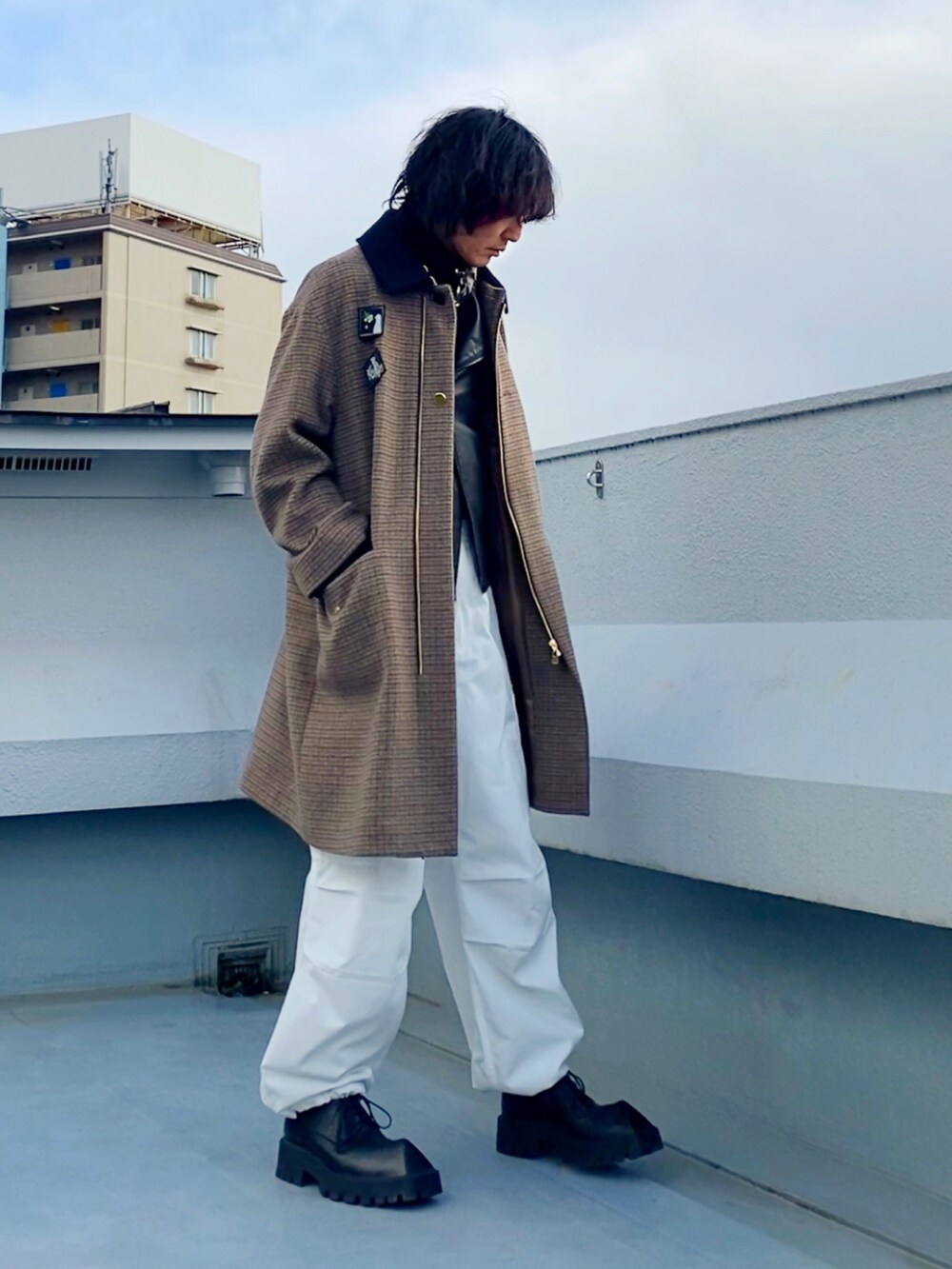 ブラック系のライダースジャケット、ブラウン系のステンカラーコート、ホワイト系のカーゴパンツを着用したメンズの冬コーディネートの3枚目の写真
