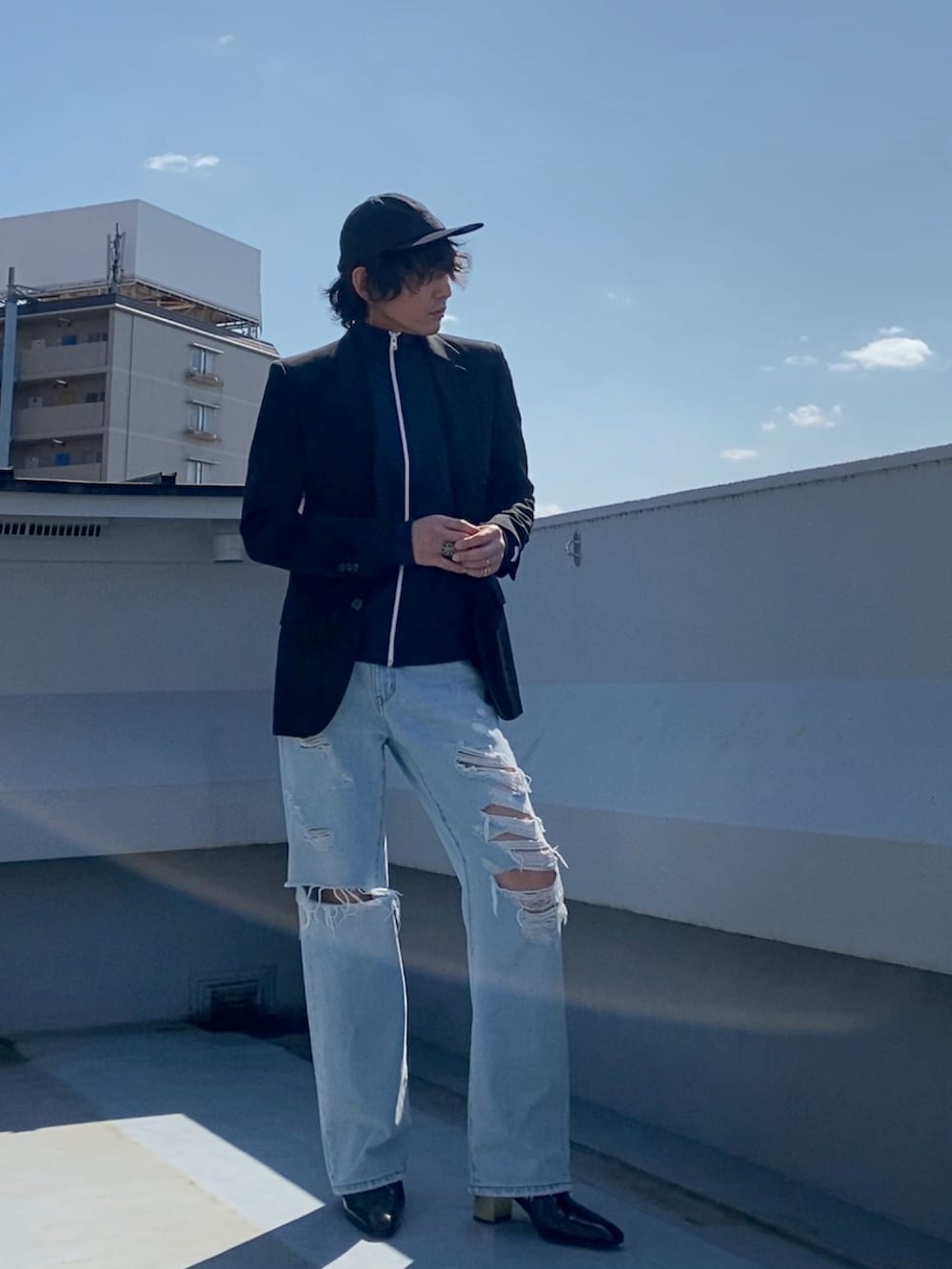 ブラック系のテーラードジャケット、ブルー系のジャージ、ブルー系のデニムパンツを着用したメンズの春コーディネートの3枚目の写真