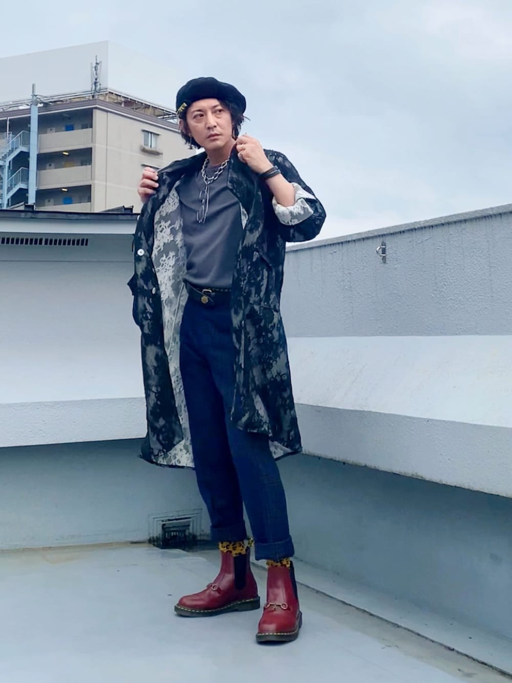 グレー系のTシャツ/カットソー、ブラック系のステンカラーコート、グリーン系のスラックスを着用したメンズの秋コーディネートの5枚目の写真