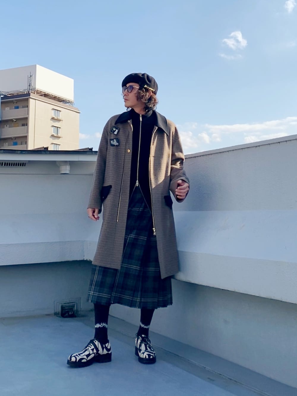 ブラウン系のステンカラーコート、ブラック系のニット/セーター、ブラウン系のスカートを着用したメンズの冬コーディネートの2枚目の写真