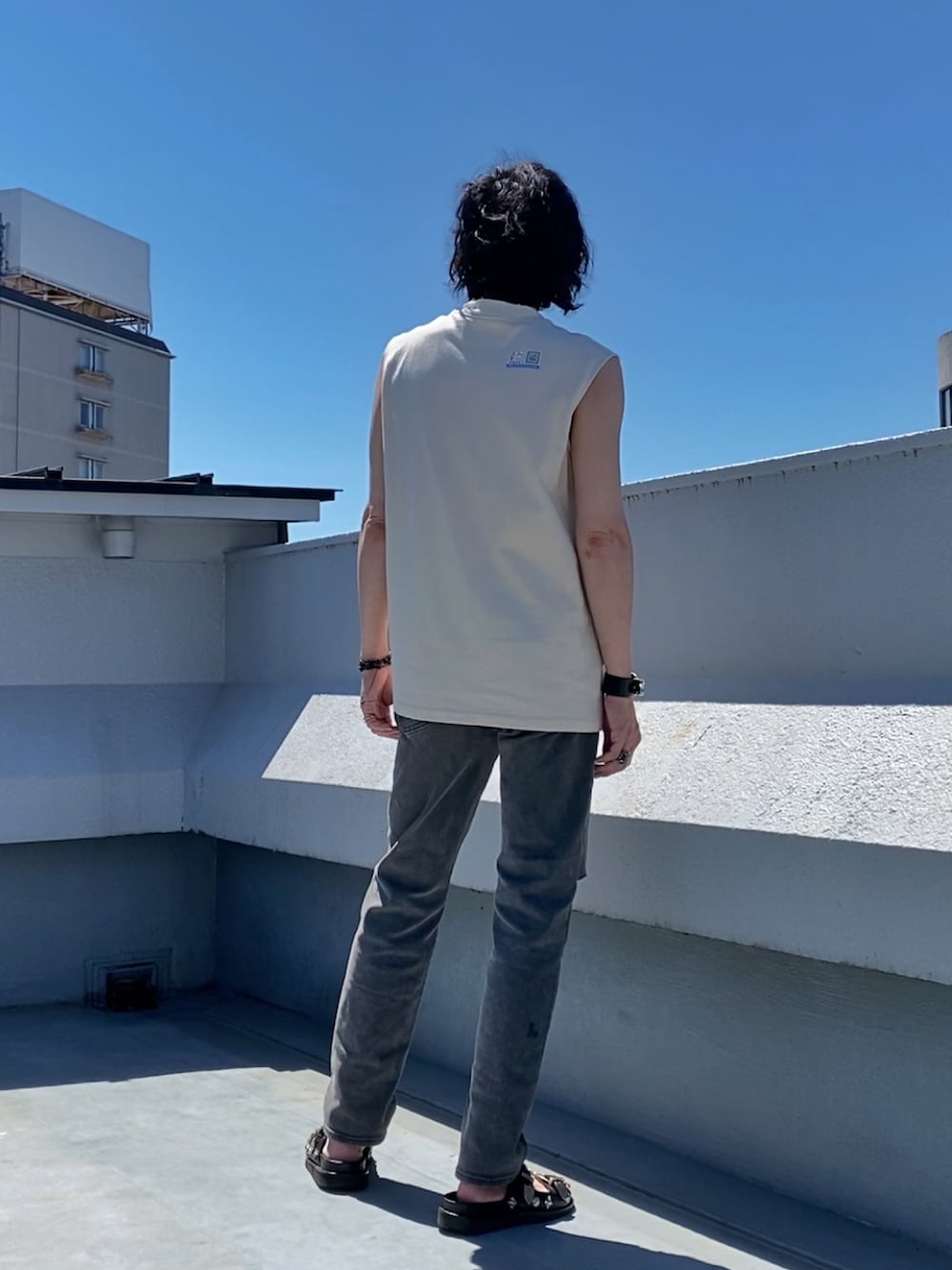 ベージュ系のTシャツ/カットソー、グレー系のデニムパンツ、ブラック系のサンダルを着用したメンズの夏コーディネートの5枚目の写真