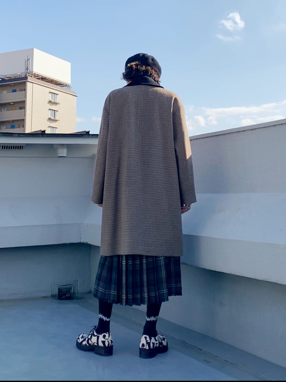 ブラウン系のステンカラーコート、ブラック系のニット/セーター、ブラウン系のスカートを着用したメンズの冬コーディネートの4枚目の写真