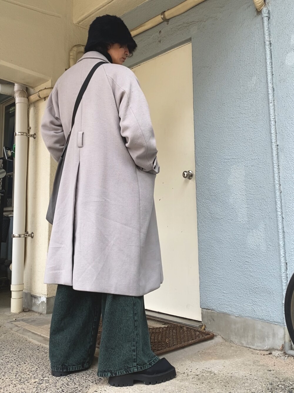 グレー系のショルダーバッグ、グレー系のチェスターコート、ブラック系のニット/セーターを着用したメンズの冬コーディネートの4枚目の写真