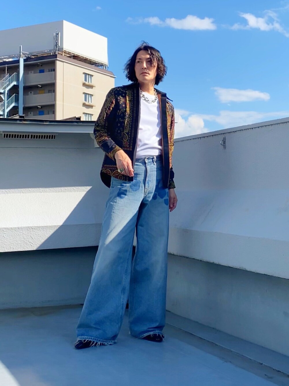 グレー系のTシャツ/カットソー、ブルー系のデニムパンツ、ブラック系のブーツを着用したメンズの秋コーディネートの5枚目の写真