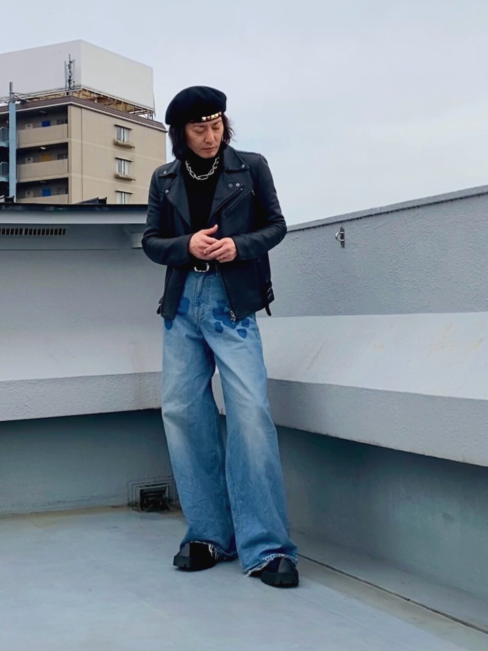 ブラック系のライダースジャケット、ブラック系のニット/セーター、ブルー系のデニムパンツを着用したメンズの春コーディネートの2枚目の写真