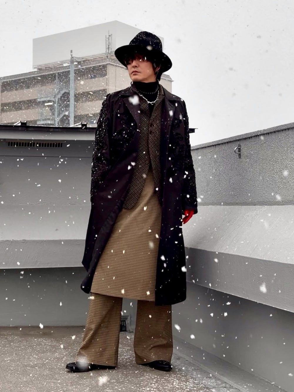 ブラック系のニット/セーター、ブラック系のステンカラーコート、ブラウン系のテーラードジャケットを着用したメンズの冬コーディネートの3枚目の写真