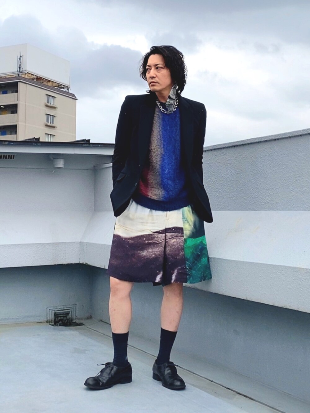 ブラック系のテーラードジャケット、ブルー系のニット/セーター、ホワイト系のその他パンツを着用したメンズの秋コーディネートの2枚目の写真
