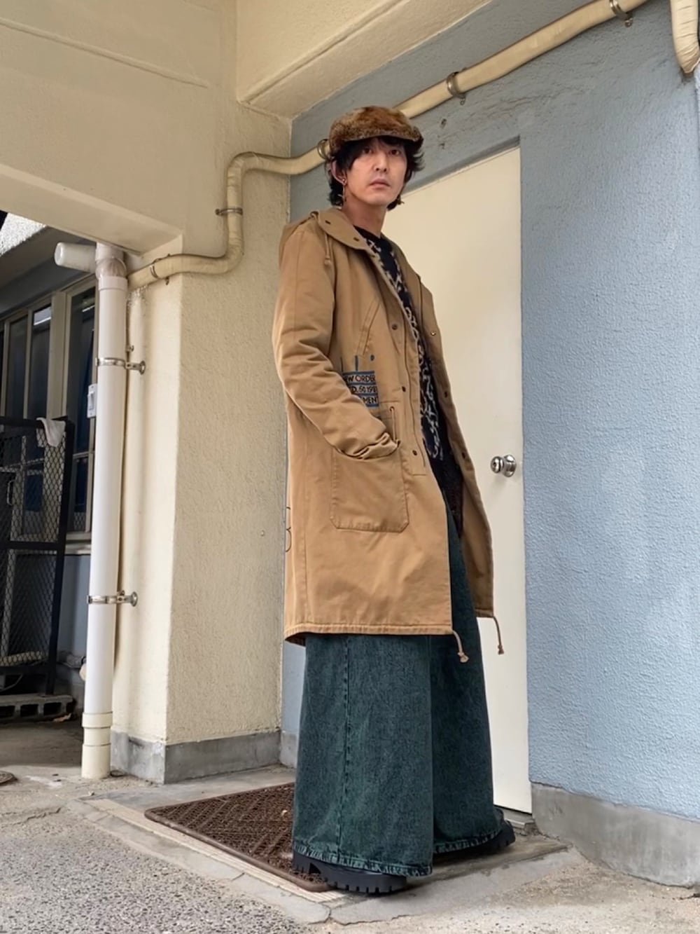 ブラック系のニット/セーター、ベージュ系のモッズコート、グリーン系のデニムパンツを着用したメンズの冬コーディネートの3枚目の写真