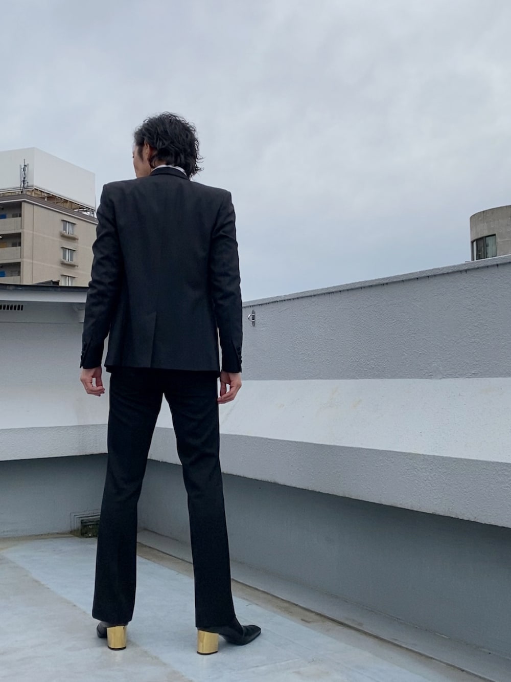 ブラック系のテーラードジャケット、ブラック系のブーツ、ブラック系のスラックスを着用したメンズの春コーディネートの4枚目の写真