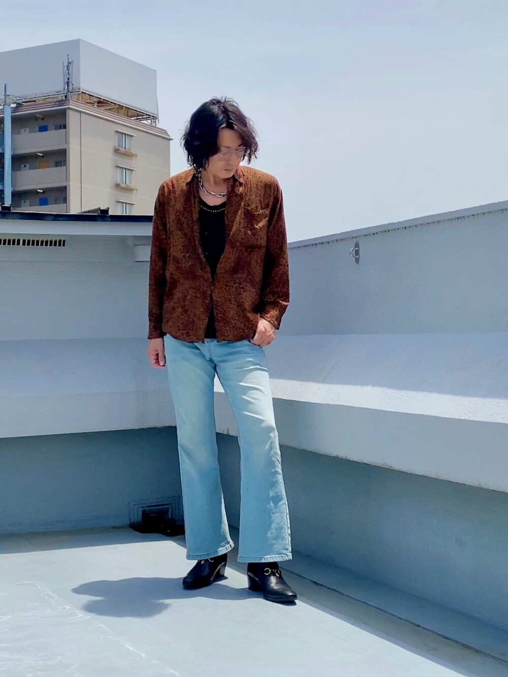 ブラウン系のシャツ/ブラウス、ブラック系のタンクトップ、ブルー系のデニムパンツを着用したメンズの春コーディネートの2枚目の写真