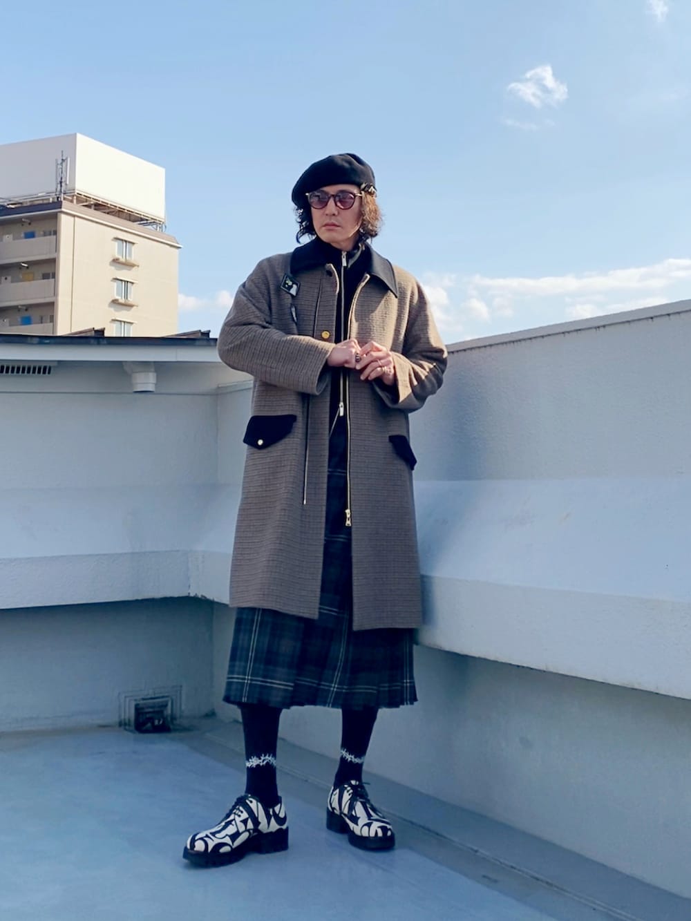 ブラウン系のステンカラーコート、ブラック系のニット/セーター、ブラウン系のスカートを着用したメンズの冬コーディネートの3枚目の写真