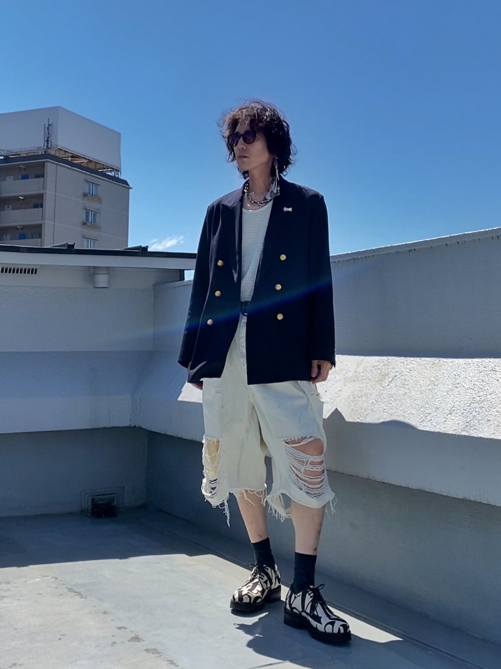 ホワイト系のタンクトップ、ブルー系のテーラードジャケット、ホワイト系のデニムパンツを着用したメンズの夏コーディネートの3枚目の写真