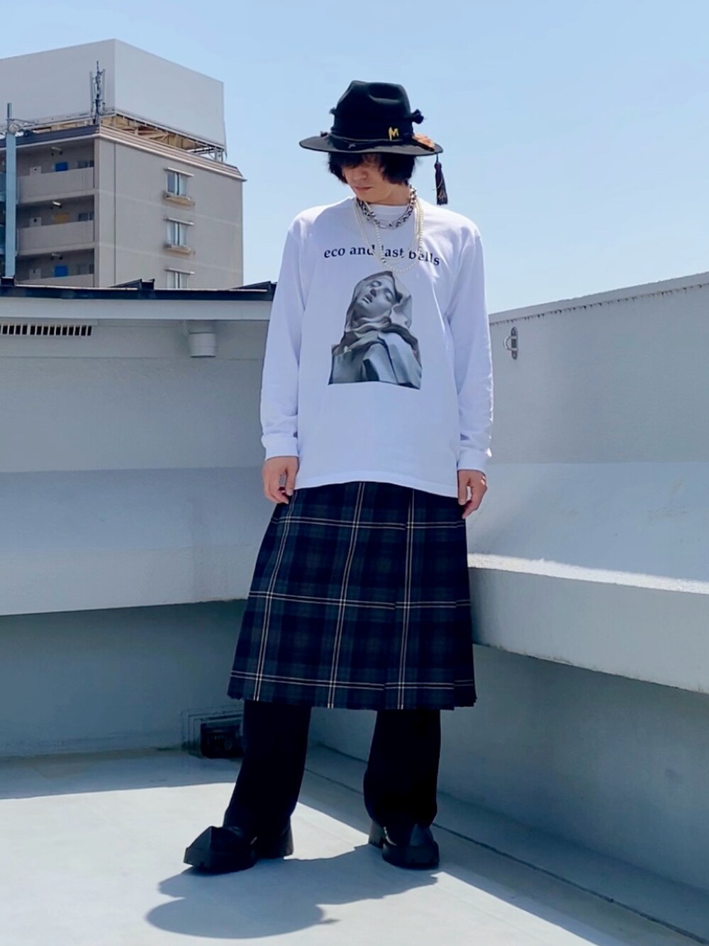 ホワイト系のTシャツ/カットソー、ブラウン系のスカート、ブラック系のスラックスを着用したメンズの春コーディネートの4枚目の写真