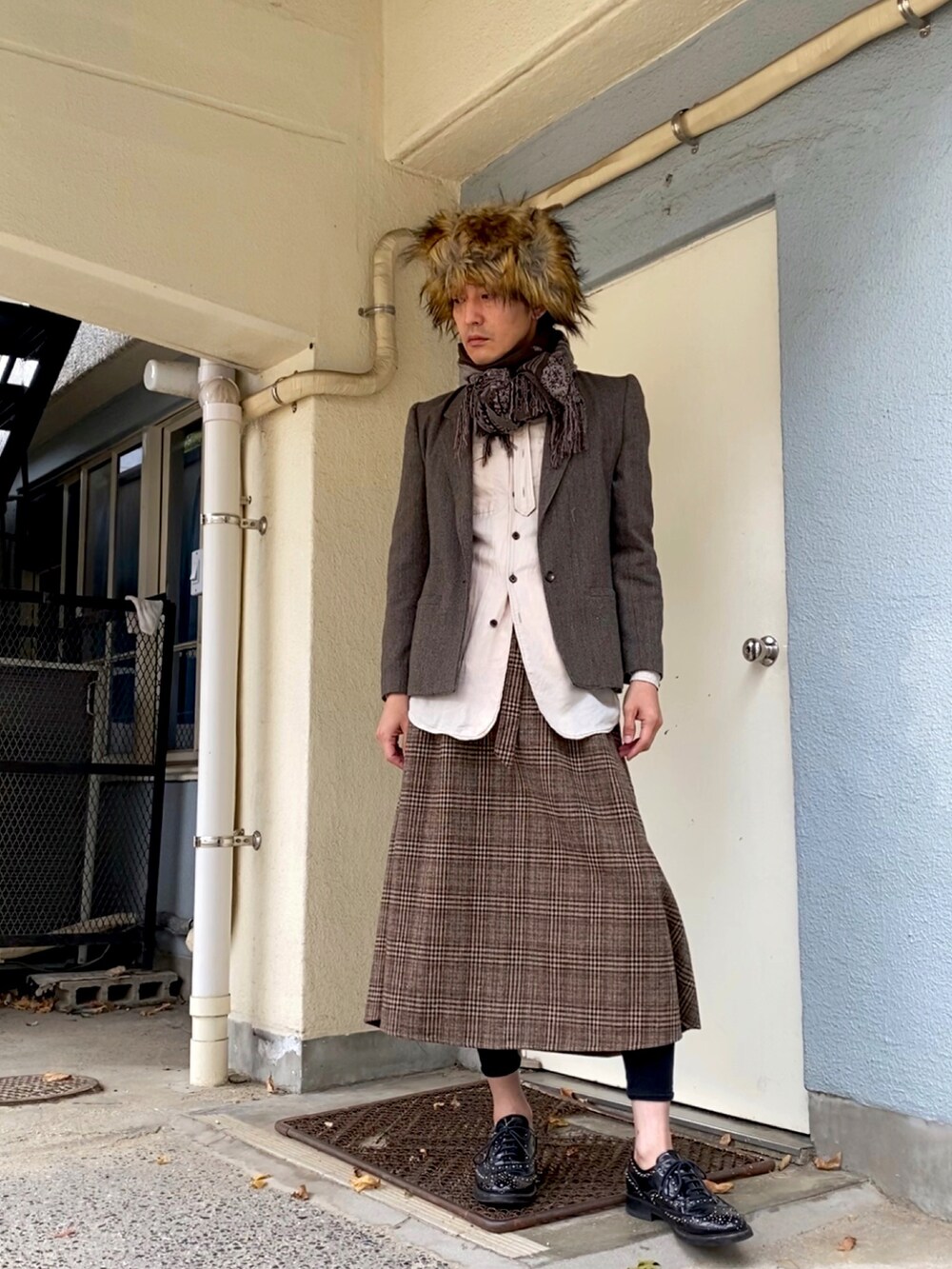 ブラウン系のテーラードジャケット、ブラック系のドレスシューズ、ブラウン系のスカートを着用したメンズの冬コーディネートの2枚目の写真