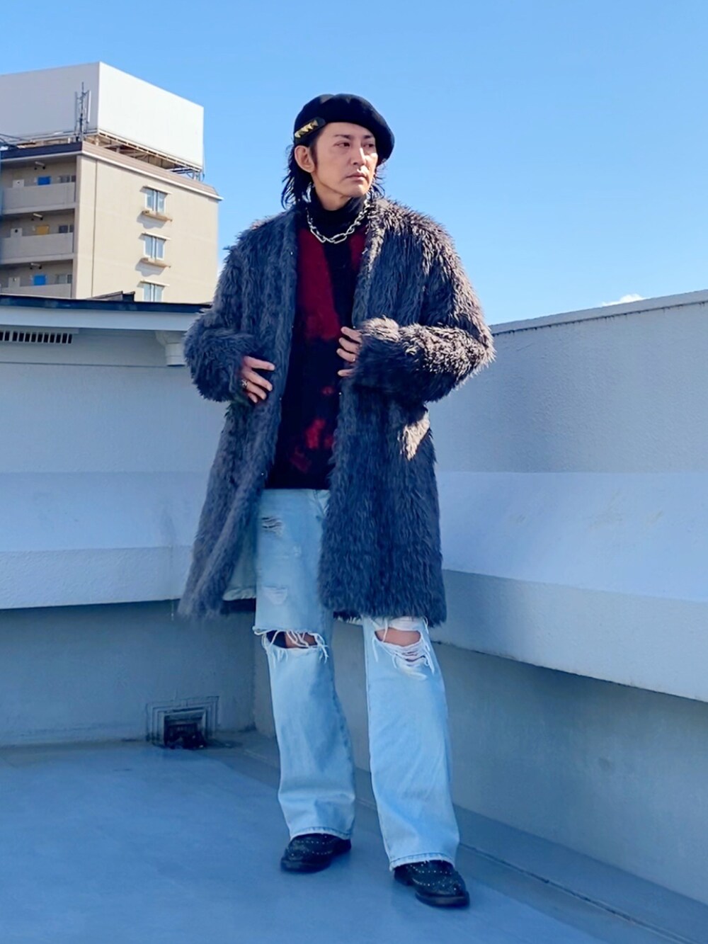 グレー系のノーカラーコート、レッド系のニット/セーター、ブラック系のニット/セーターを着用したメンズの冬コーディネートの2枚目の写真