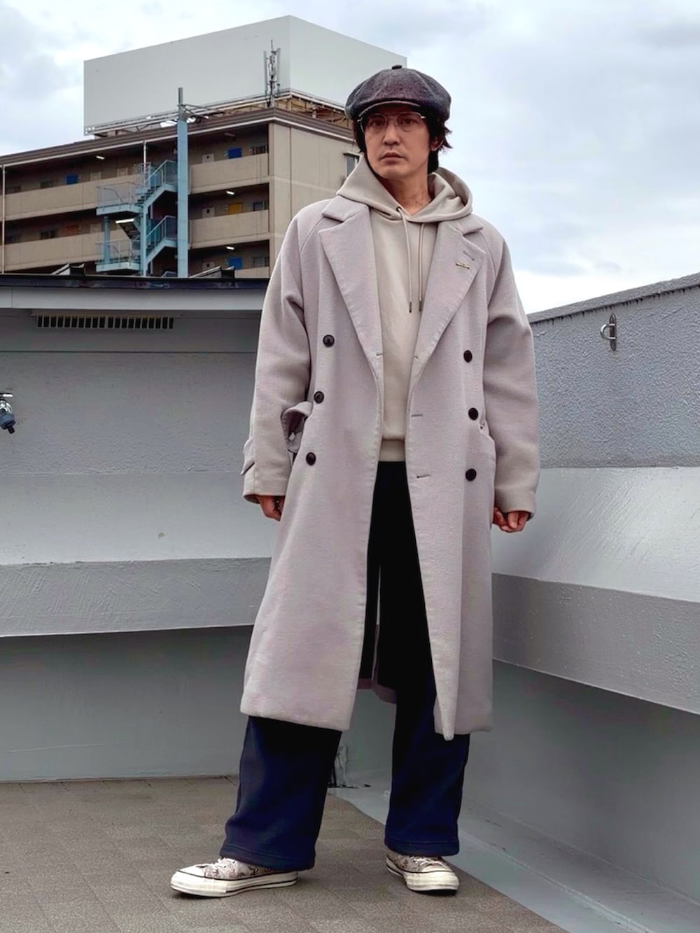 グレー系のチェスターコート、ベージュ系のパーカー、グレー系のその他パンツを着用したメンズの冬コーディネートの4枚目の写真