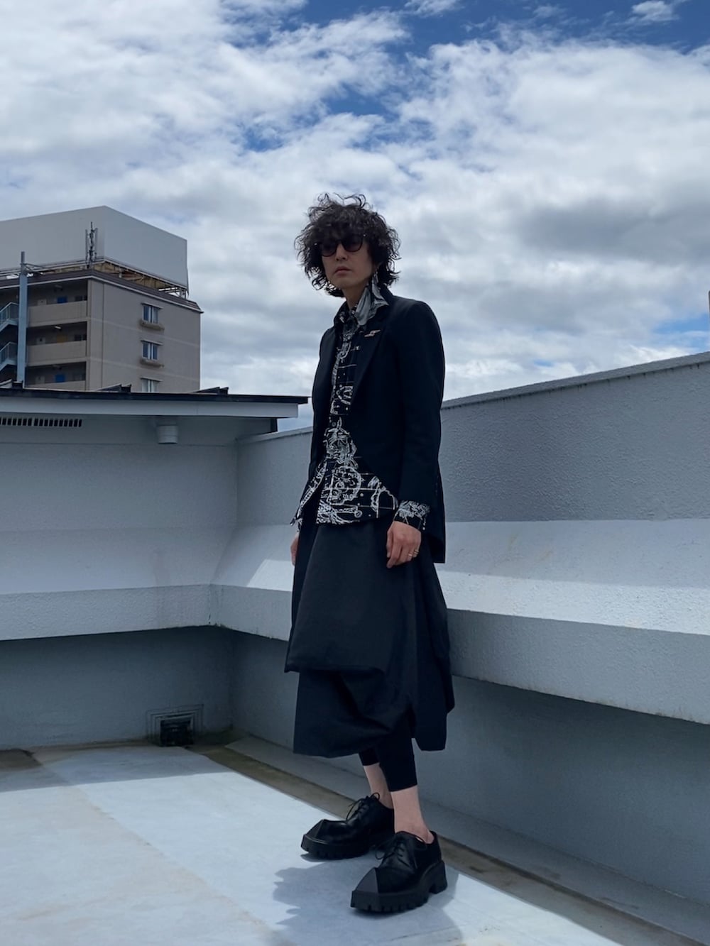 ブラック系のテーラードジャケット、ブラック系のシャツ/ブラウス、ブラック系のスカートを着用したメンズの春コーディネートの2枚目の写真