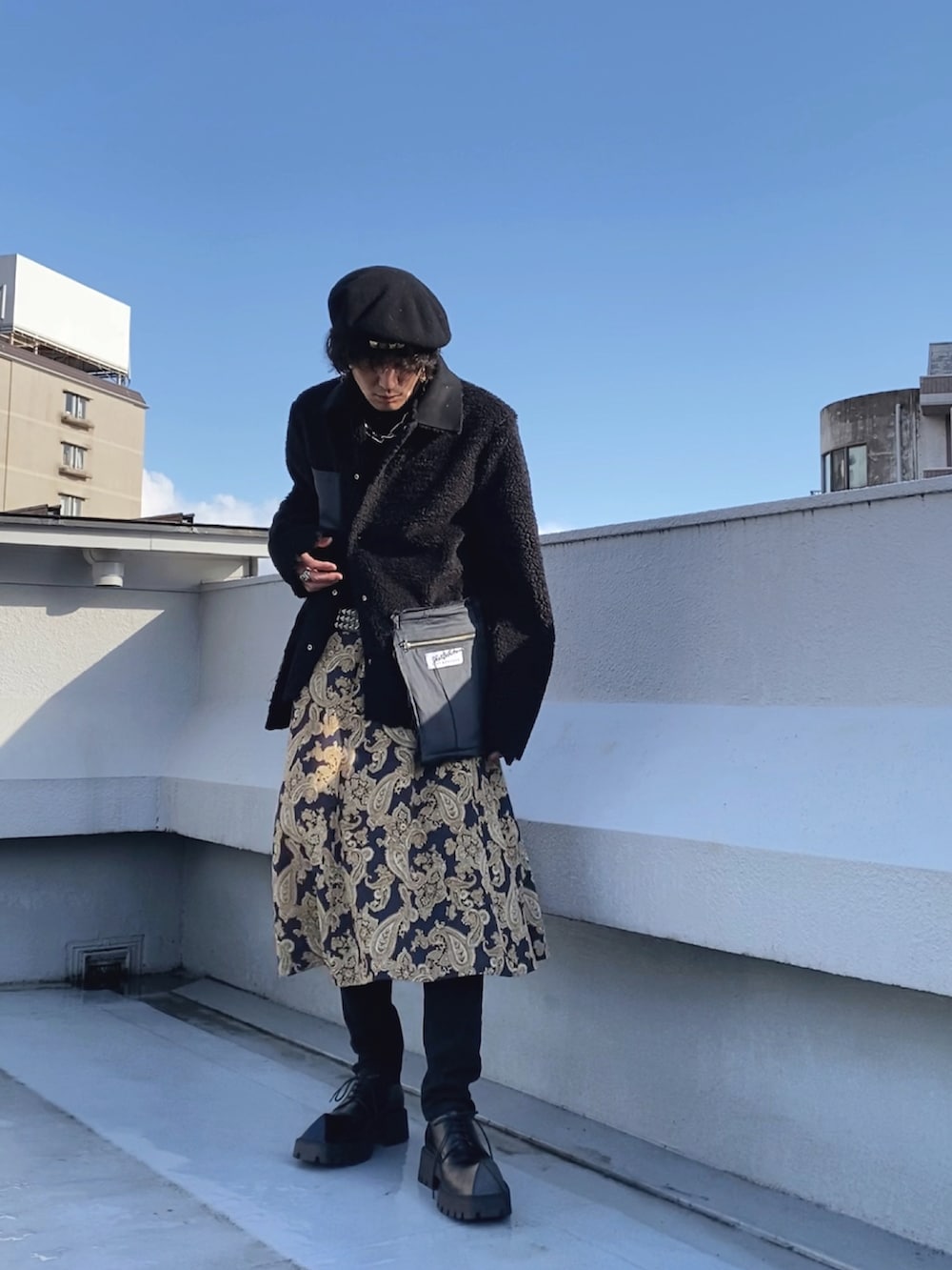 ブラック系のムートンコート、ブルー系のスカート、ブラック系のドレスシューズを着用したメンズの春コーディネートの2枚目の写真