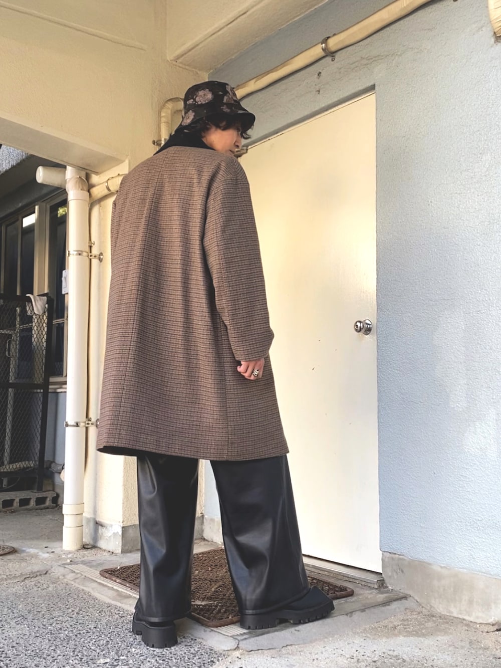 ブラウン系のステンカラーコート、ブルー系のニット/セーター、ブラック系のその他パンツを着用したメンズの冬コーディネートの3枚目の写真