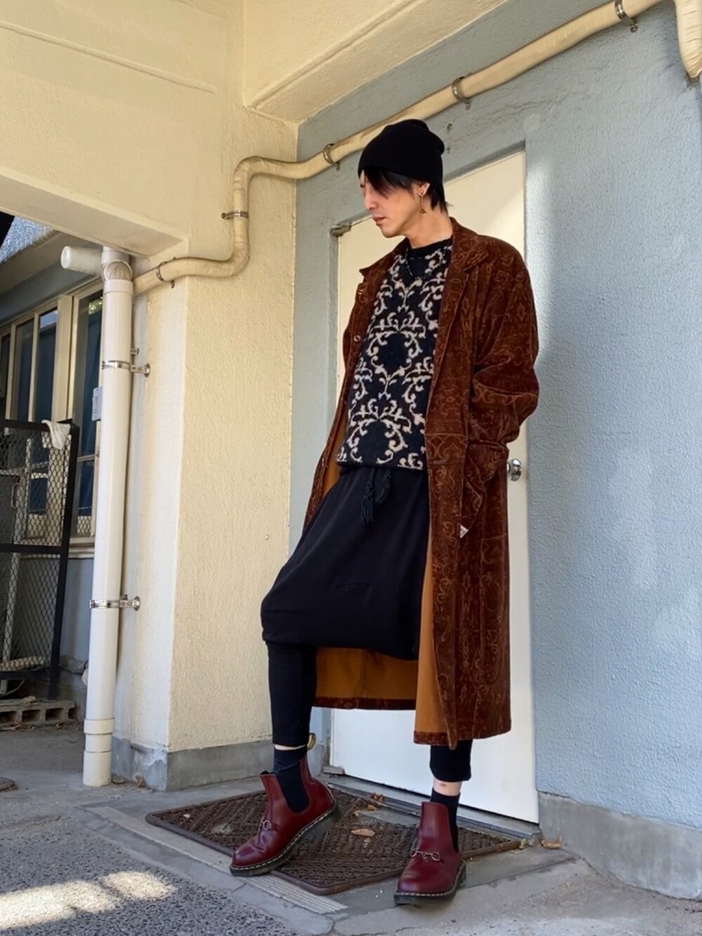 ブラック系のニット/セーター、ブラウン系のその他アウター、ブラック系のその他パンツを着用したメンズの冬コーディネートの2枚目の写真