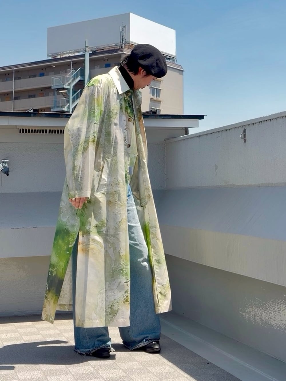 ブルー系のデニムパンツ、ブラック系のニット/セーター、グリーン系のステンカラーコートを着用したメンズの春コーディネートの4枚目の写真