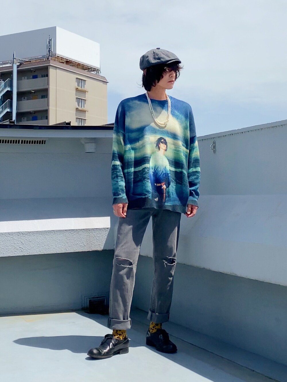 ブルー系のニット/セーター、グレー系のデニムパンツ、ブラック系のドレスシューズを着用したメンズの春コーディネートの2枚目の写真