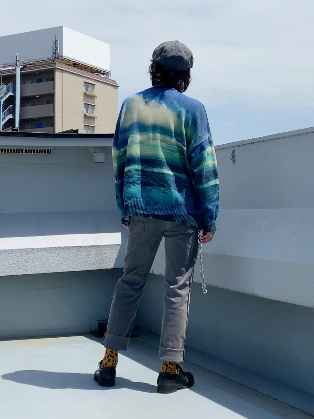 ブルー系のニット/セーター、グレー系のデニムパンツ、ブラック系のドレスシューズを着用したメンズの春コーディネートの4枚目の写真