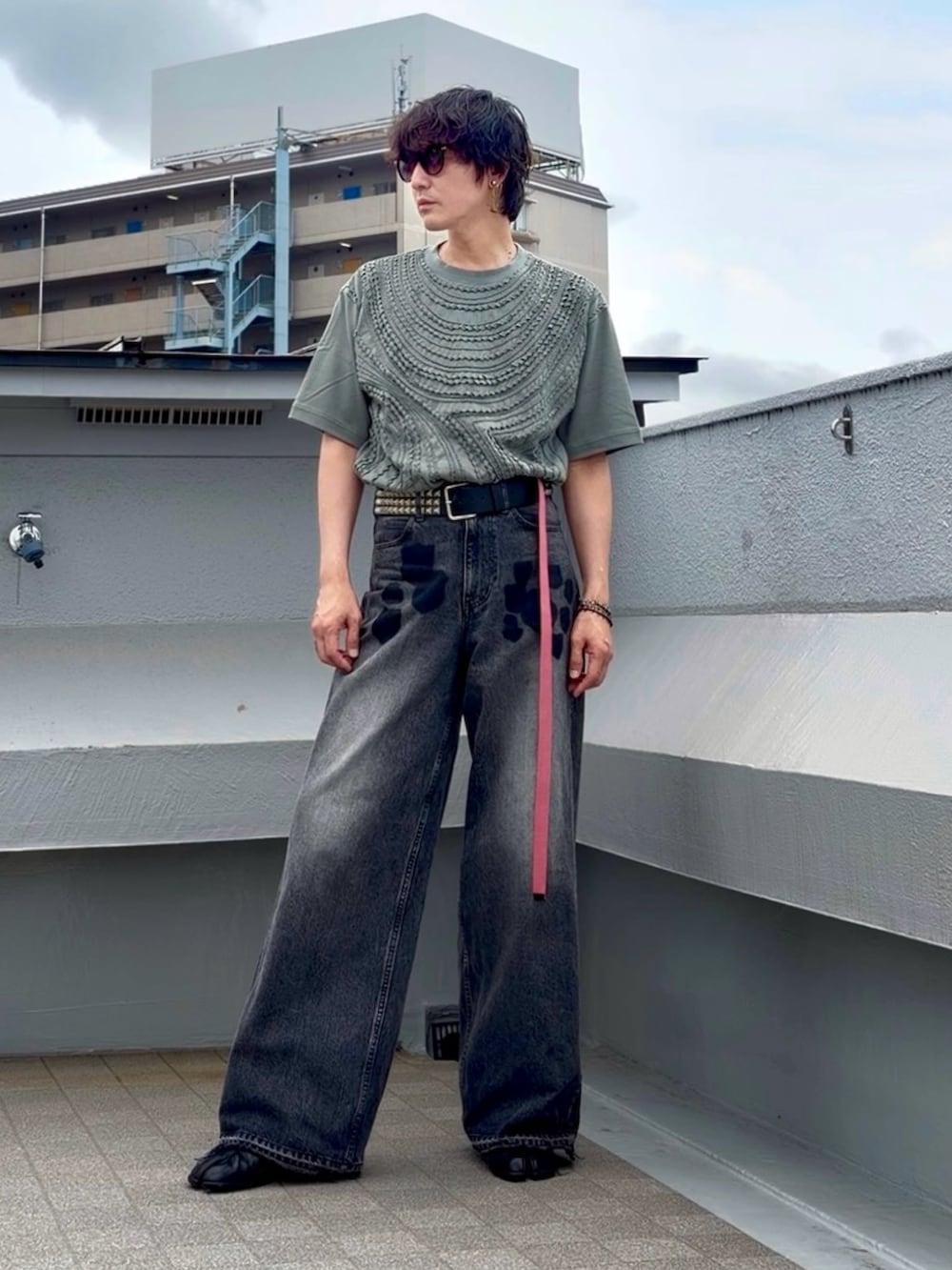 ブラック系のデニムパンツ、ブラック系のブーツ、グリーン系のTシャツ/カットソーを着用したメンズの夏コーディネートの2枚目の写真