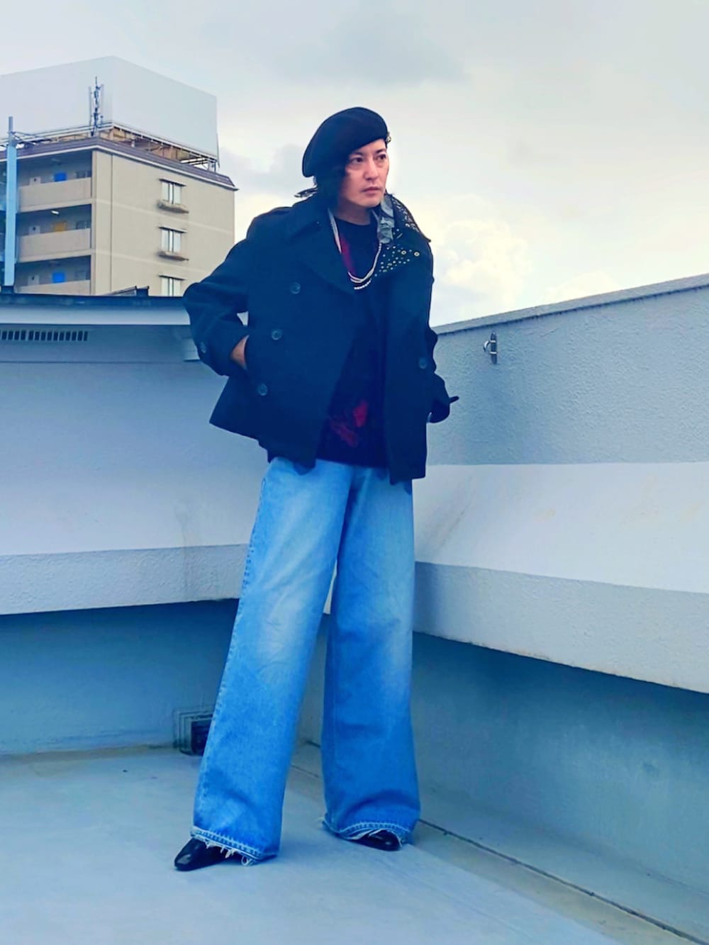 ブラック系のピーコート、レッド系のニット/セーター、ブルー系のデニムパンツを着用したメンズの冬コーディネートの3枚目の写真