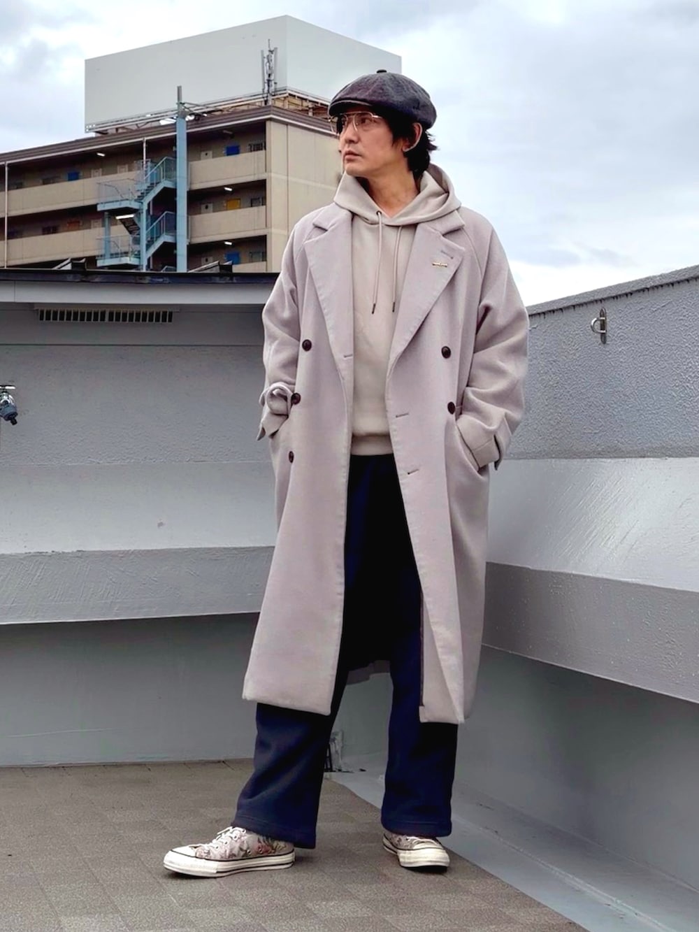 グレー系のチェスターコート、ベージュ系のパーカー、グレー系のその他パンツを着用したメンズの冬コーディネートの2枚目の写真